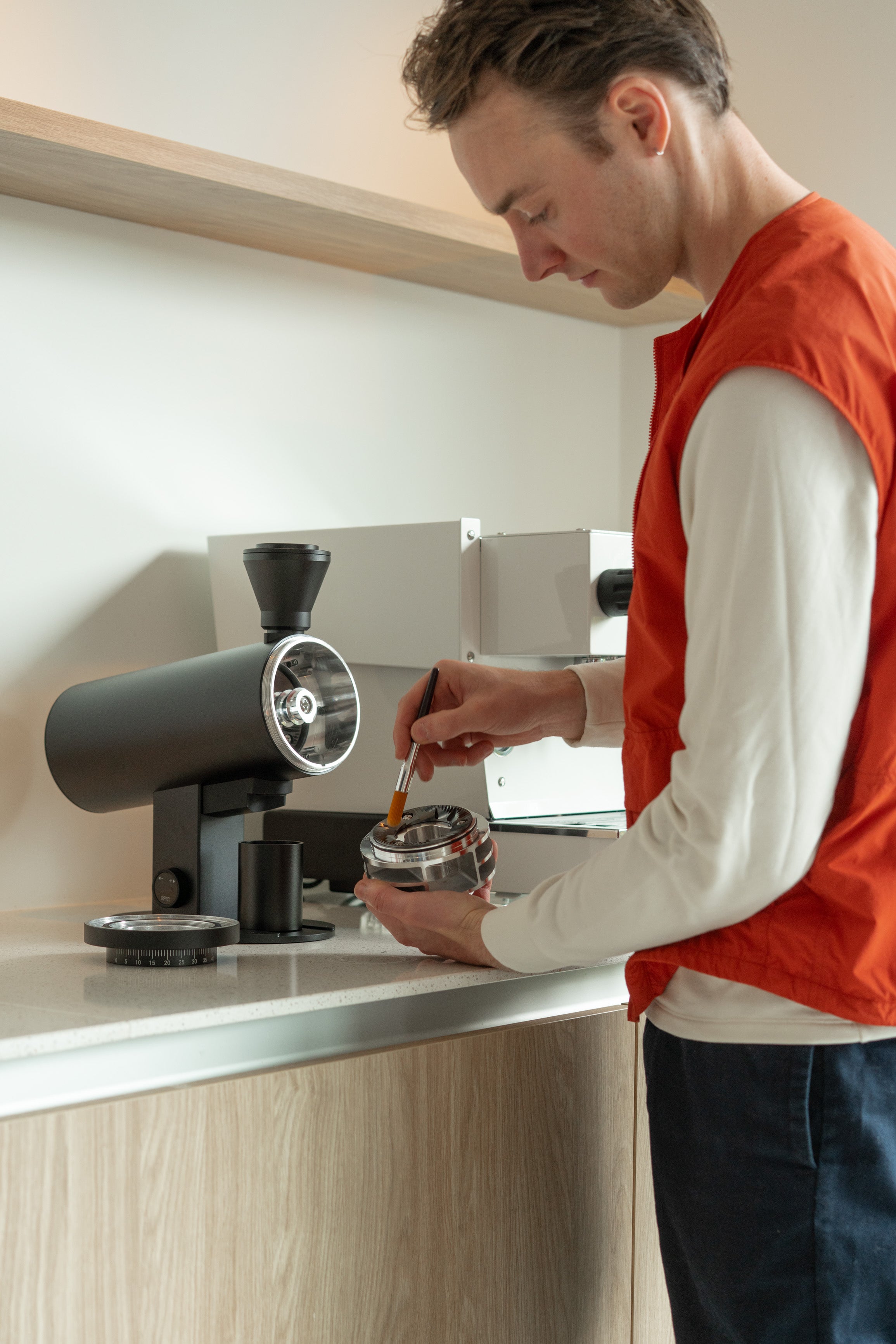 Freek van FREKKO die een maalschijf van een DF koffiemolen schoonmaakt door af te vegen met een kwastje.